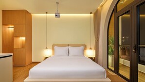 A hotel room with a bed, bedside lamps, a wardrobe, and a sliding glass door to a balcony. - Dalat Blanc Residence (Cam Ly - Da Lat)
