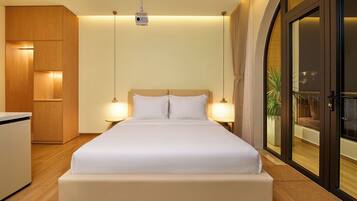 A hotel room with a bed, bedside lamps, a wardrobe, and a sliding glass door to a balcony.