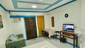 Una habitación de hotel con cama, escritorio, televisor y ventilador.