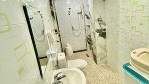 Un baño con lavamanos, inodoro, ducha y espejo.