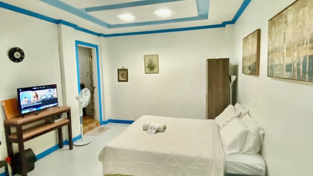 Un dormitorio con cama, sofá, televisor y escritorio.