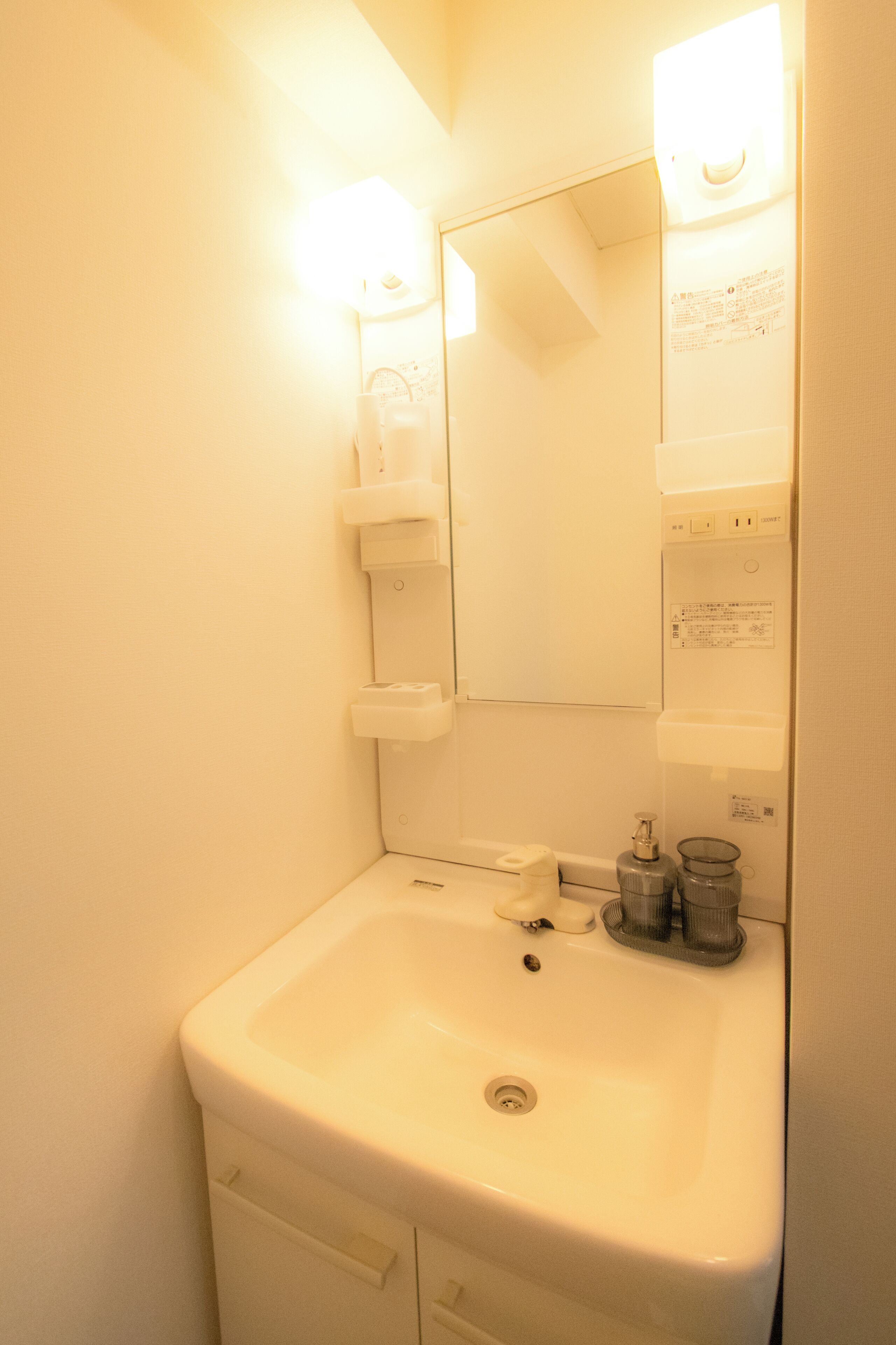 A bathroom with a sink, mirror, and two light fixtures.