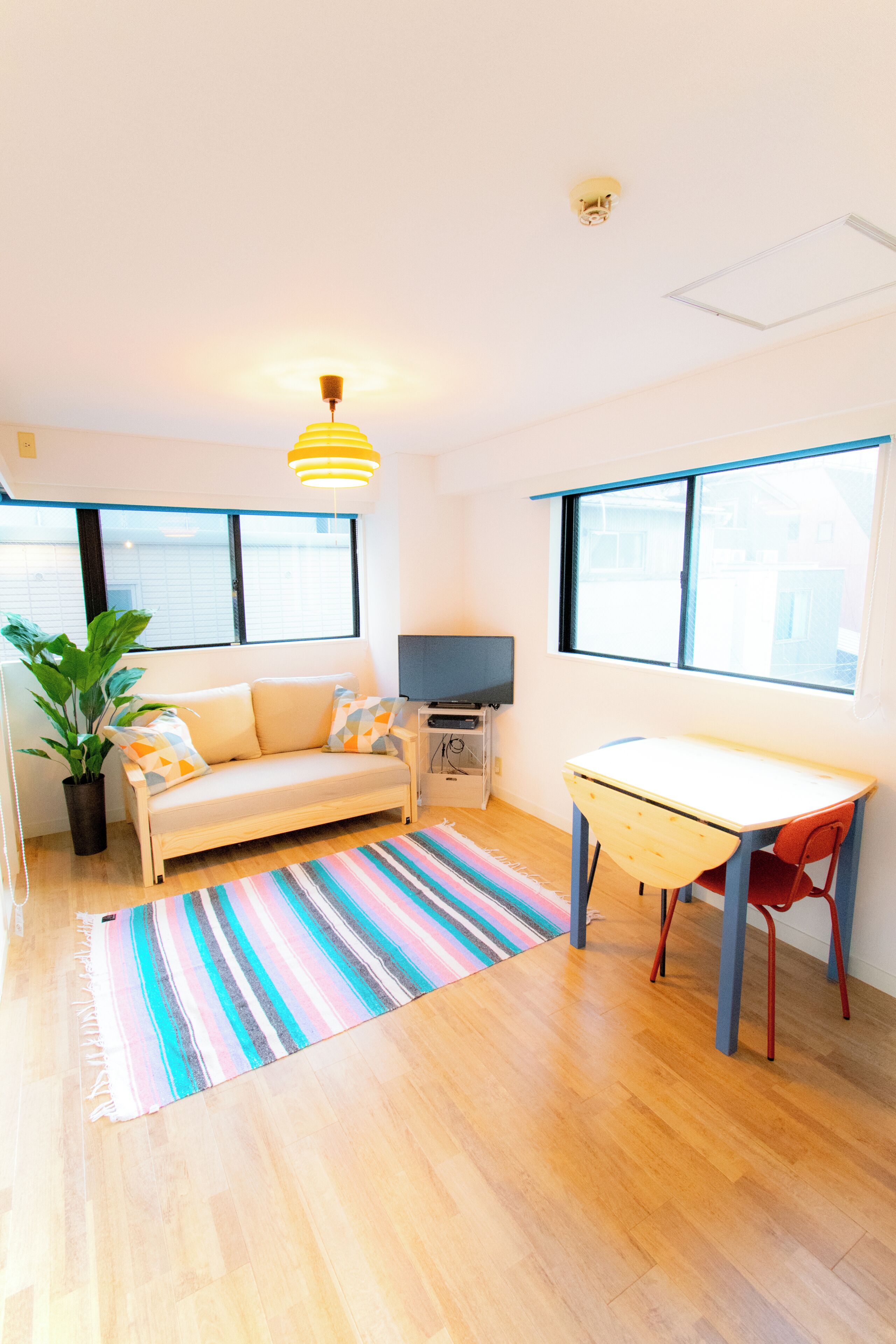 Una habitación con sofá, mesa, televisor y planta en maceta.
