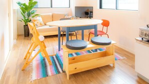 A modern living room with a sofa, dining table, chairs, a TV, and a potted plant. - Kobayashi Building 302 (Tokyo)