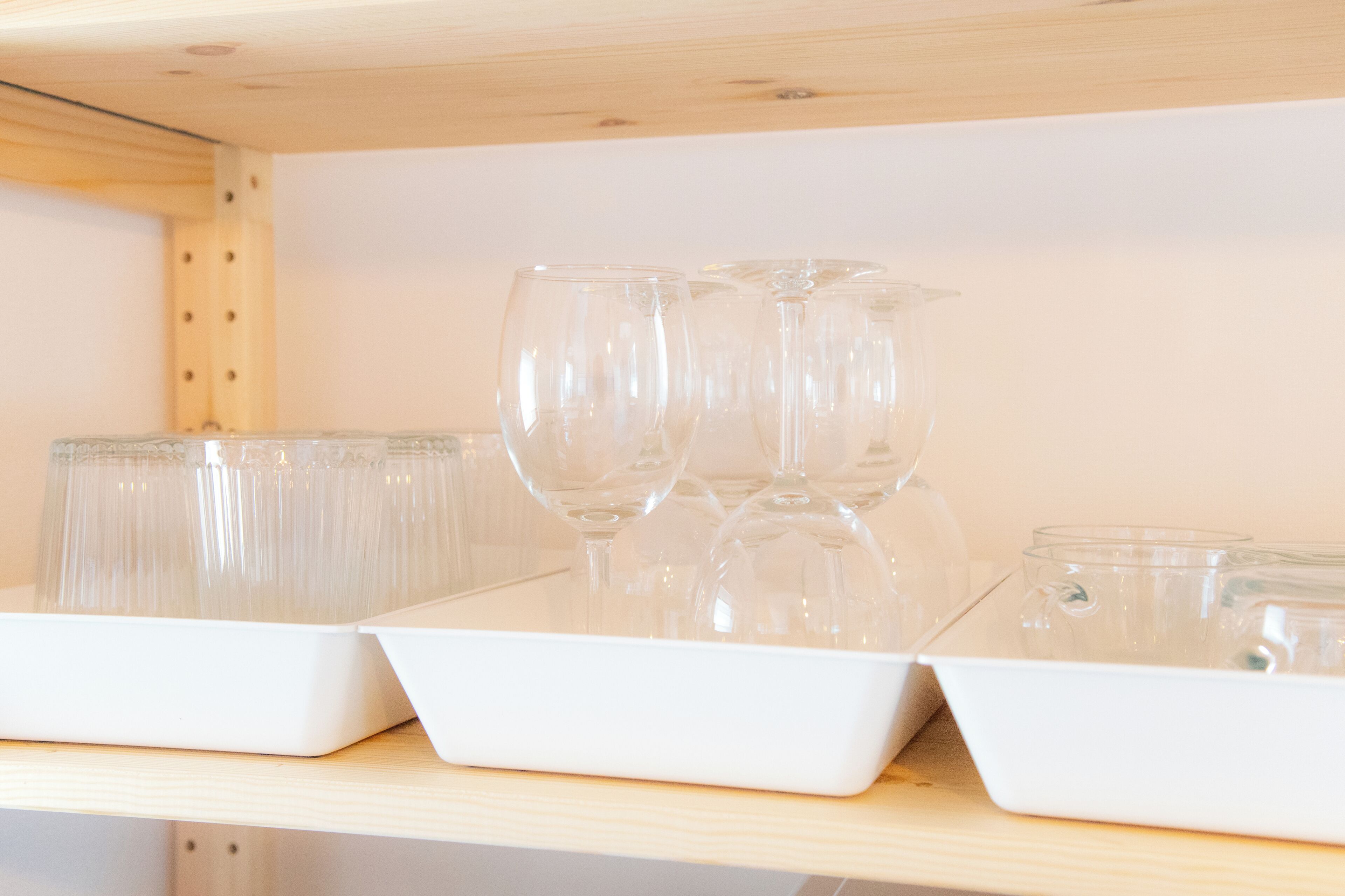 A shelf with clear glassware and plastic containers.