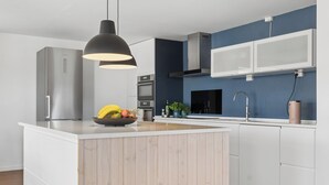Una cocina moderna con una isla central, electrodomésticos de acero inoxidable y una pared de acento azul.