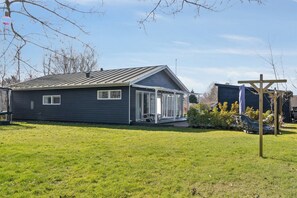 A single-story house with a covered porch, a lawn, and a wooden structure to the right. - Lovely holiday home near beach and nature (Vejby)