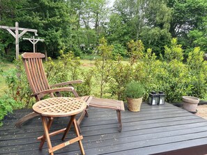 A wooden deck with two chairs and a table, surrounded by greenery and trees. - Lovely holiday home near beach and nature (Vejby)