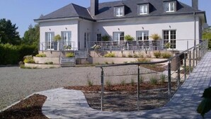Un bâtiment à deux étages, avec un toit gris, des murs blancs et un petit porche doté de marches menant à l’entrée.