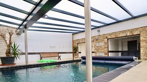Une piscine intérieure avec un banc et une plante en pot.