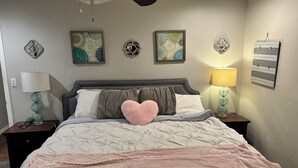 Ein Schlafzimmer mit einem Bett, zwei Nachttischen, einem Deckenventilator und Wanddekorationen.