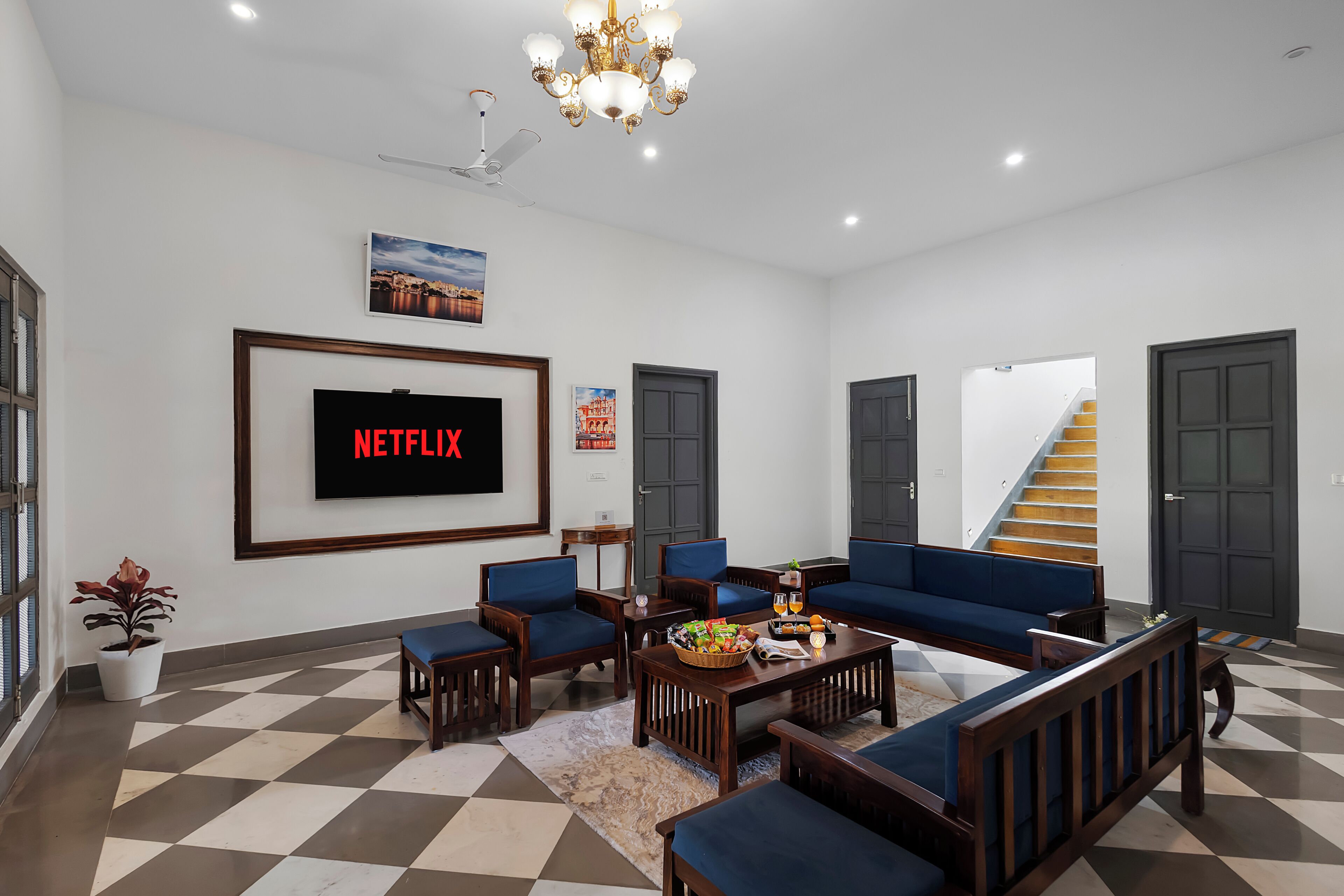 Uma sala de estar com sofá, cadeiras, mesa de centro, televisão e escada.