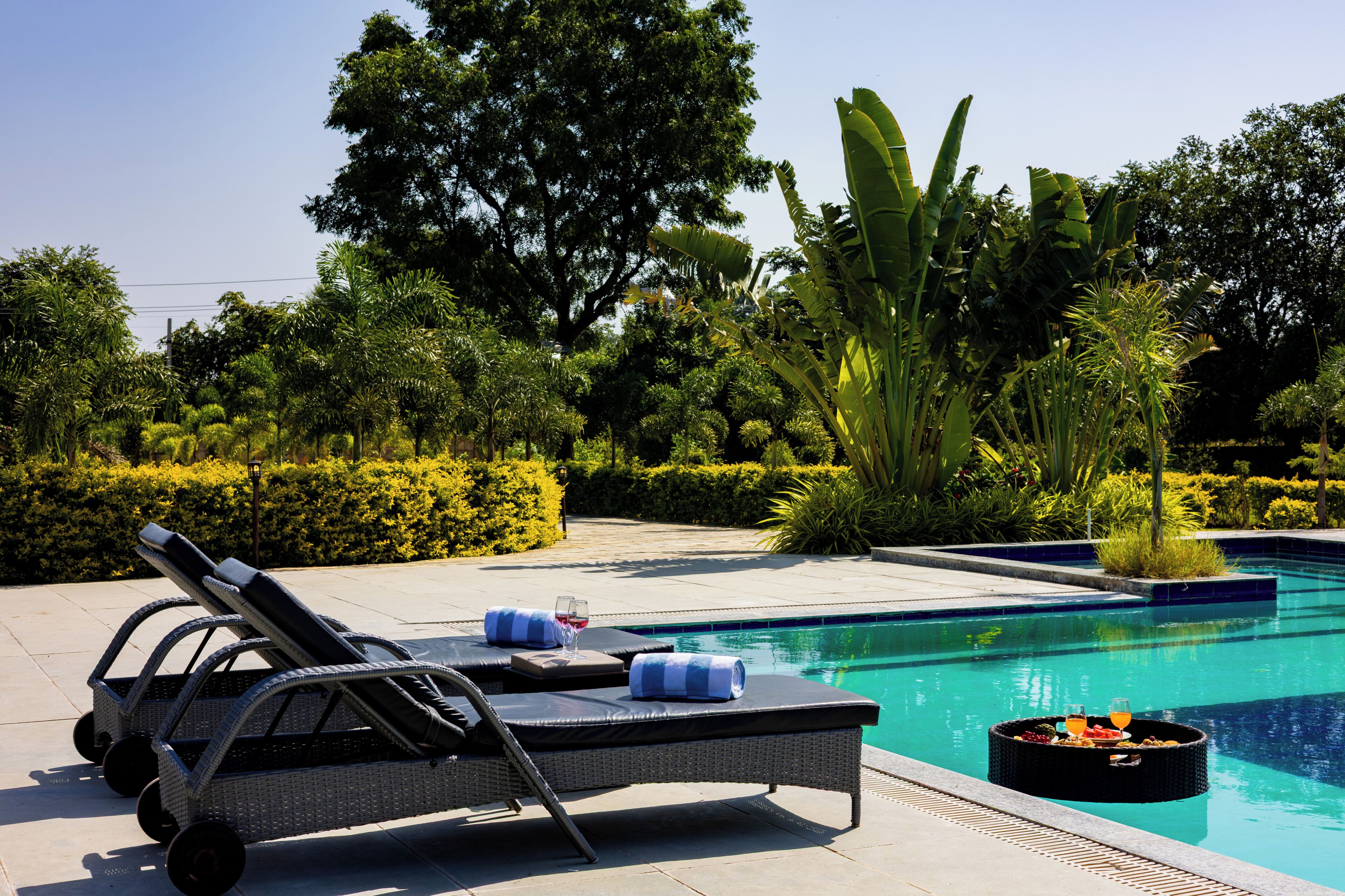 A pool area with lounge chairs, a floating bar, and lush greenery.