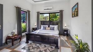 A bedroom with a large bed, a window with curtains, a bedside table with a lamp, and a potted plant. - Alaya Stays Aravale Farm 4BHK Petfrndly (Sohna)
