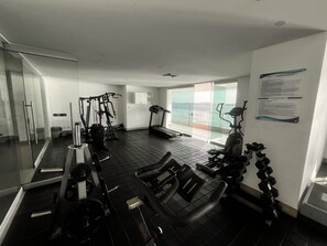 A gym with various exercise equipment, a treadmill, and a view of the sea through large windows. - Palmetto Sunset Laguito 3-Bedroom Oceanfront (Cartagena)