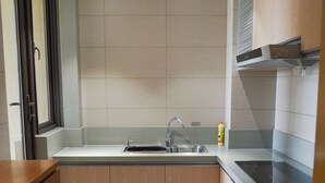 A modern kitchen with wooden cabinets, a stainless steel sink, and a built-in oven. - PengLai Mahota Town (Yantai)