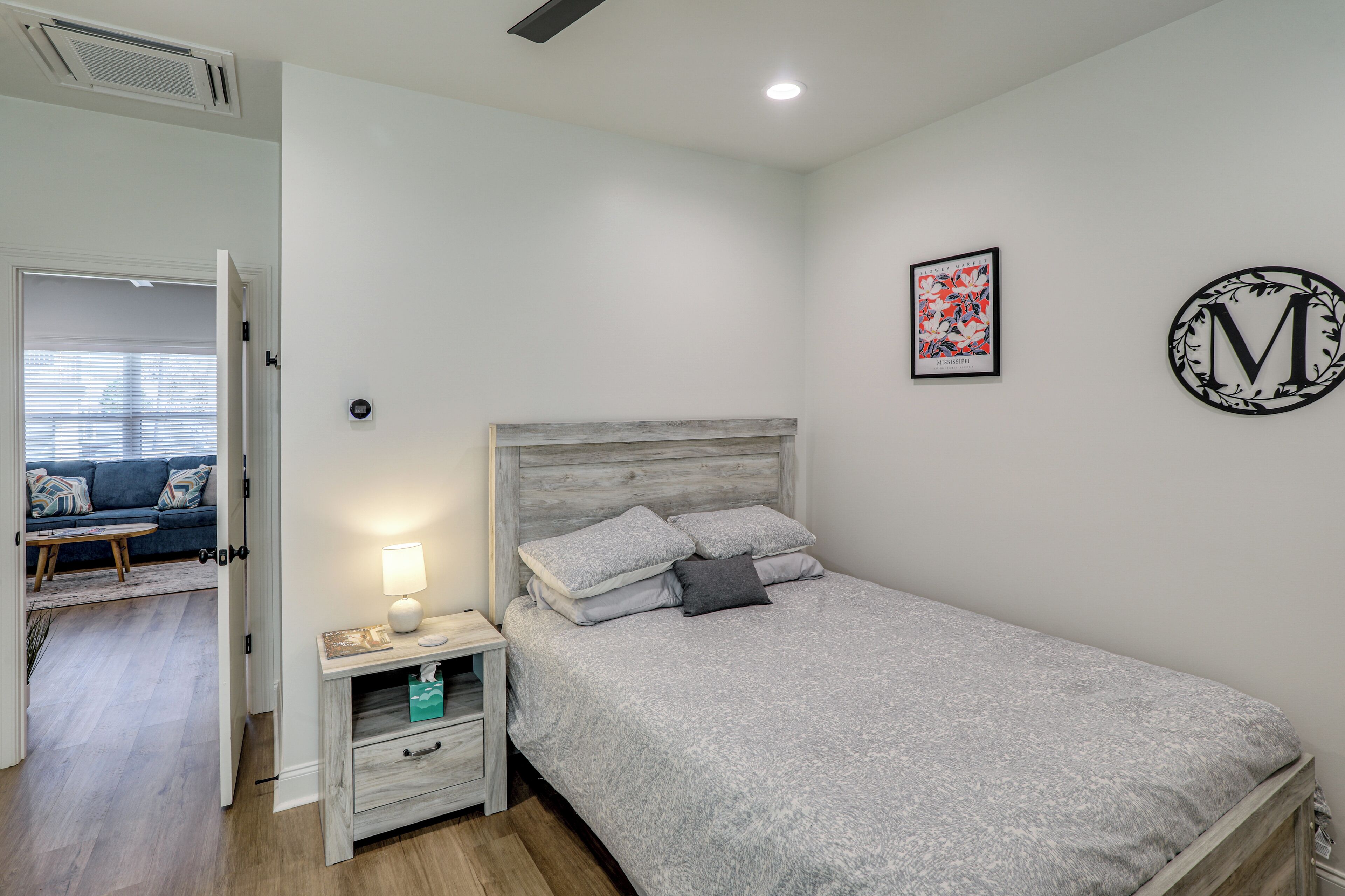Una camera da letto con un letto, comodino, lampada e un'opera d'arte appesa al muro.