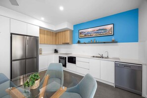 Eine moderne Küche mit Essbereich, Edelstahlgeräten und einer blauen Akzentwand.