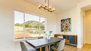 Uma área de refeições com uma janela grande, um candelabro e um quadro na parede.