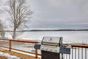 A grill on a deck with a view of a frozen lake. - Lake Access & Pier: Northwoods Fishing Cabin (Pearson)