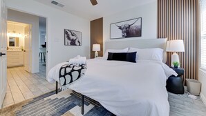 A bedroom with a bed, bedside lamps, a ceiling fan, and a large window with blinds. - < 1 Mi to Historic McKinney: Modern Duplex w/ Yard (McKinney)