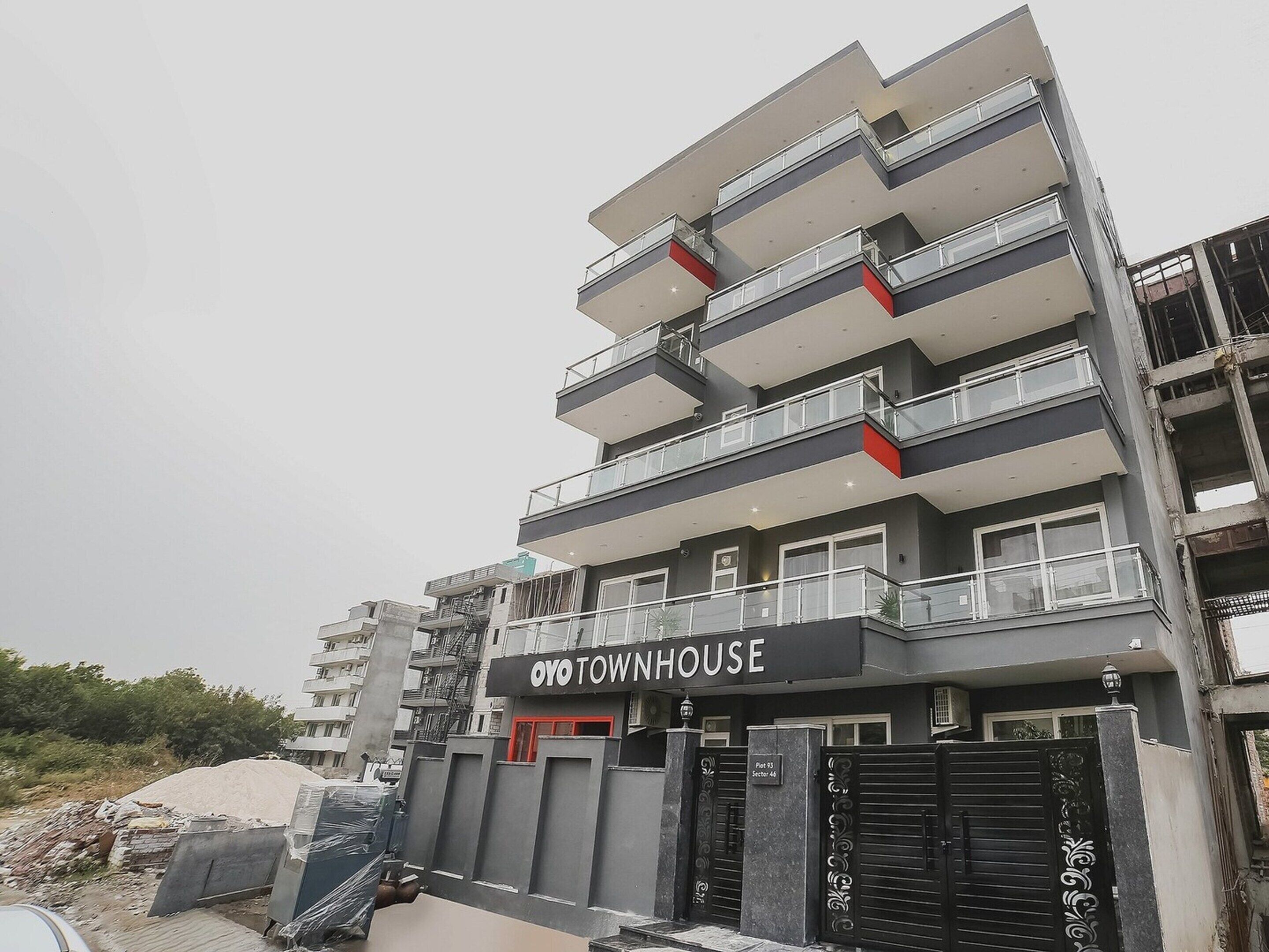 A multi-story building with balconies, a sign reading 'OYO TOWNHOUSE,' and a gated entrance.