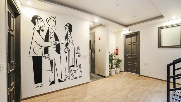 A hallway with a wall mural, wooden flooring, a staircase, and a door. - Townhouse Sector 46 Gurgaon Near Appu Ghar (Gurugram)