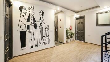 Un pasillo con un mural en la pared, suelo de madera, una escalera y una puerta.