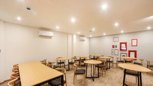 A conference room with multiple tables and chairs, air conditioning units on the walls, and framed pictures on the wall. - Townhouse Sector 46 Gurgaon Near Appu Ghar (Gurugram)