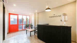 A reception area with a wooden floor, a red door, a black reception desk, and a wall-mounted sign reading 'TOWNHOUSE'. - Townhouse Sector 46 Gurgaon Near Appu Ghar (Gurugram)