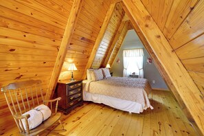 A wooden-paneled room with a bed, a nightstand, a chair, and a dresser. - Pond Mountain Springs 'Falcon Cabin,' Fish & Hike! (Eureka Springs)