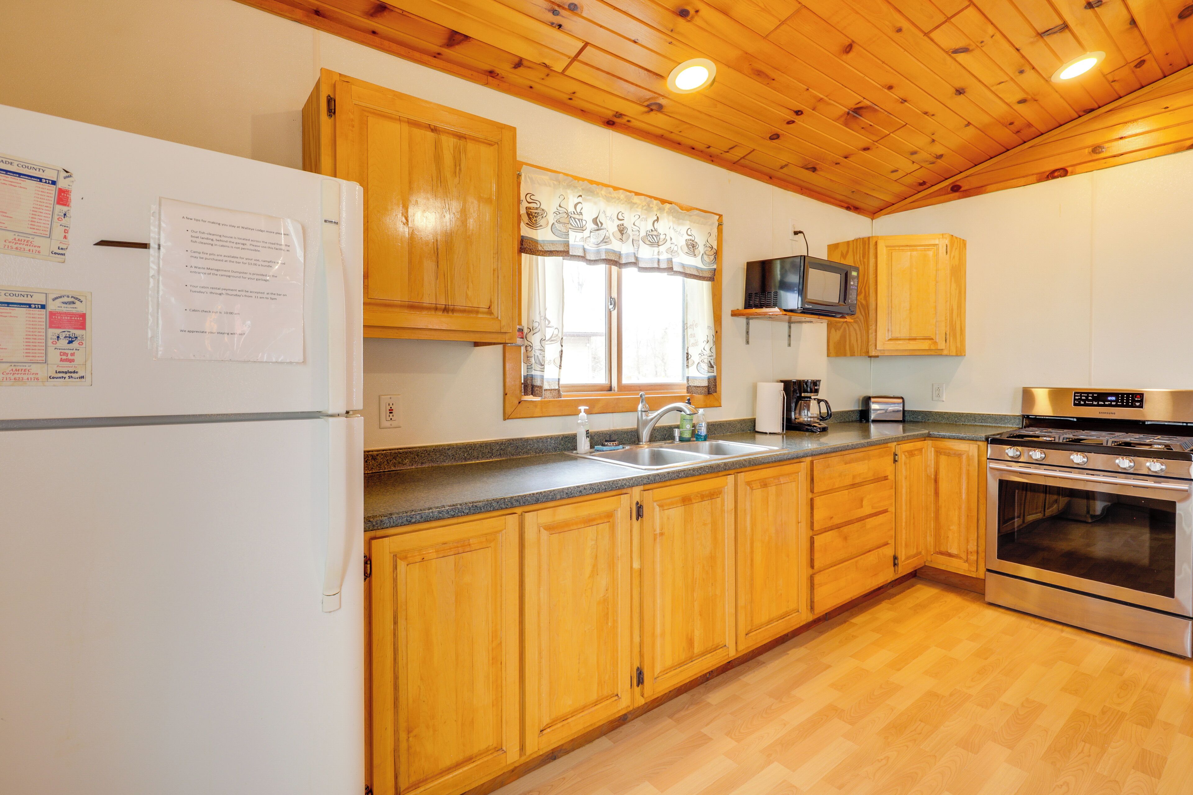 Una cocina con armarios de madera, estufa de acero inoxidable, microondas y refrigerador.