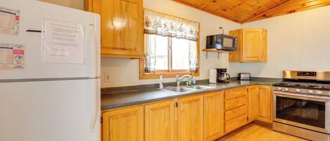 Una cocina con armarios de madera, estufa de acero inoxidable, microondas y refrigerador.