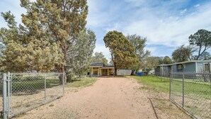 A single-story house with a front porch, surrounded by a gravel driveway and chain-link fences. - Payson Pines & Porch Vibes: Cool High Country Base (Payson)
