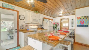 A kitchen with wooden cabinets, a microwave, and a dining area with a wooden table and chairs. - Payson Pines & Porch Vibes: Cool High Country Base (Payson)
