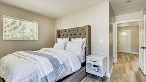 Un dormitorio con cama, mesita de noche y ventana con persianas.