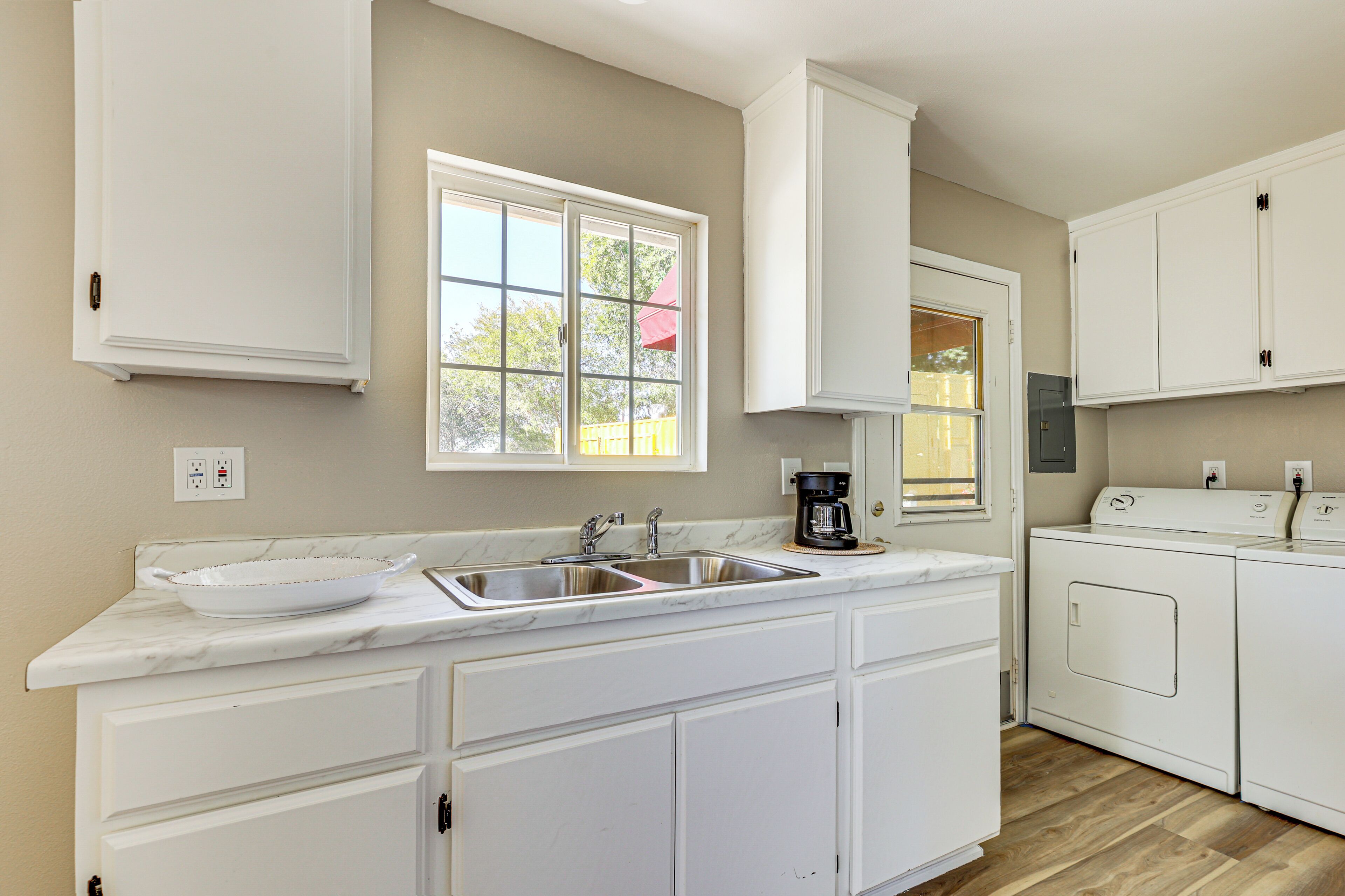 A kitchen with a marble countertop, a sink, a coffee maker, and a washing machine.