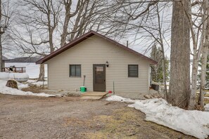 A small, single-story house with a front door, two windows, and a small porch. - Fish, Float & Ride the Trails! Northwoods Retreat (Pearson)