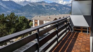 A balcony with a view of mountains, a railing, and a building with a flat roof. - Cosy Apartment in a Central Location (Veysonnaz)