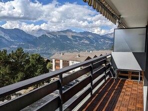 A balcony with a view of mountains, a railing, and a building with a flat roof. - Cosy Apartment in a Central Location (Veysonnaz)