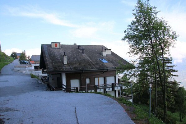 A building with a sloped roof, a small porch, and a view of the landscape. - Cozy Apartment With Mountain Views (Sion)