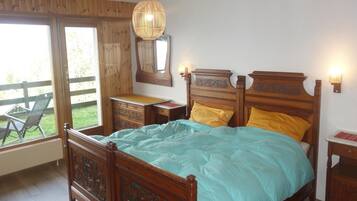 A bedroom with a wooden bed, a dresser, a mirror, and a hanging light fixture.