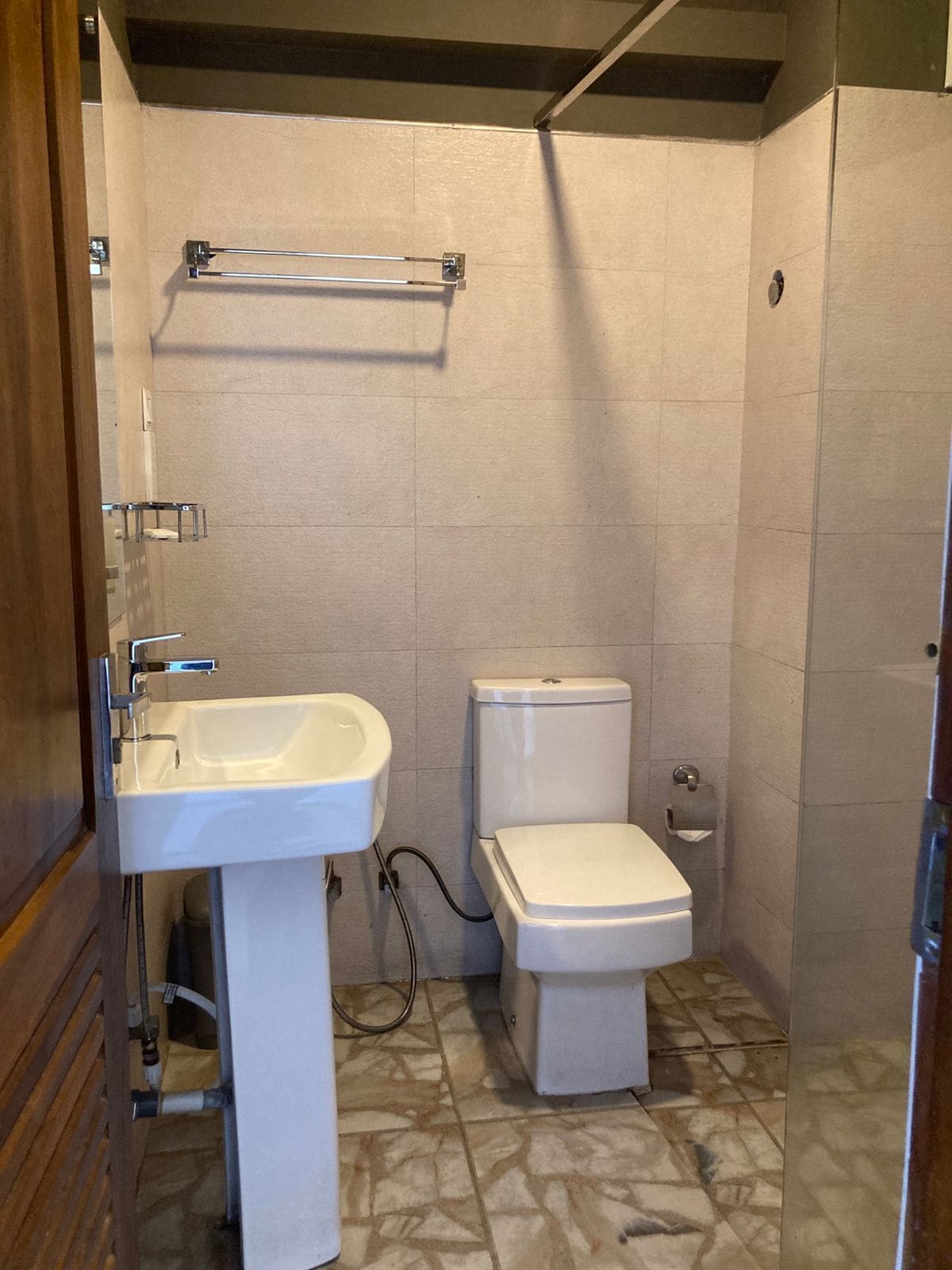 A bathroom with a pedestal sink, toilet, and a towel rack.