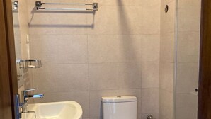 A bathroom with a white sink, toilet, and shower area. - Hotel Sandriana Kandy (Kandy)