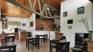 A spacious indoor area with wooden beams, tiled flooring, and multiple seating arrangements. - Sol Samara (Sámara)