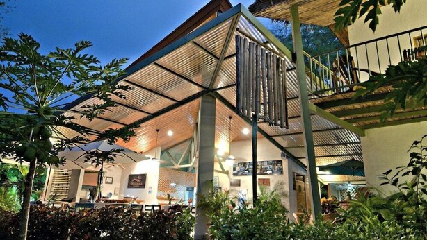 A modern building with a large open space, a balcony, and a covered area with plants. - Sol Samara (Sámara)