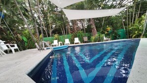 A swimming pool with clear blue water, surrounded by greenery and white lounge chairs. - Sol Samara (Sámara)