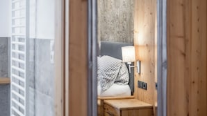 A wooden interior with a bed, a nightstand, and a wall-mounted lamp. - Gasthof Stern (Oetz)