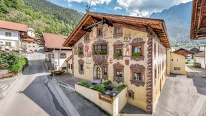 A traditional building with ornate windows and a sloped roof, surrounded by a street and mountains. - Gasthof Stern (Oetz)