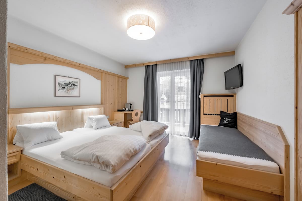 Un dormitorio con dos camas, televisión, escritorio y ventana con cortinas.